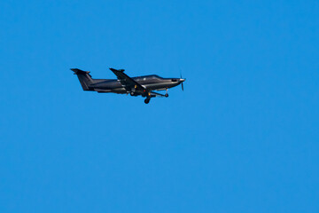 Fototapeta na wymiar Black airplane flying in clear blue sky