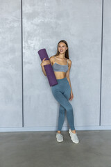 Sports woman holding a fitness mat in her hands on at home