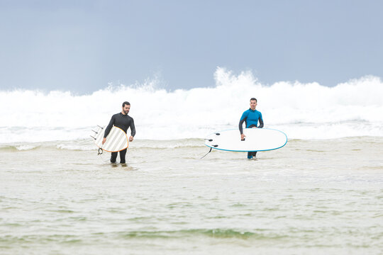 Male surfers walking in sea before riding wave