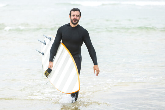Male surfer walking in sea before riding wave