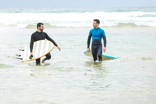 Male surfers walking in sea before riding wave