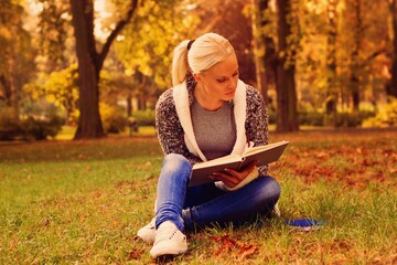 Book reading in park. Autumn time.