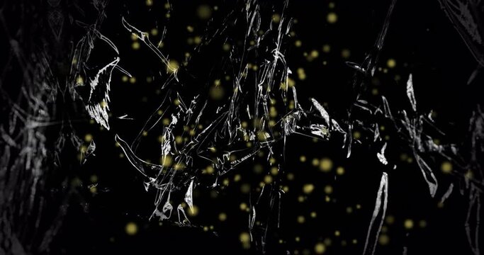 Animation of yellow particles floating over light on moving shiny black plastic