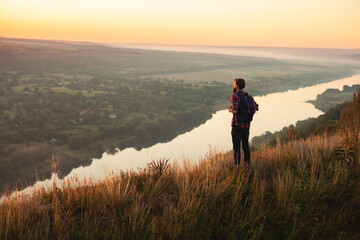 Male traveler admiring river at sunset