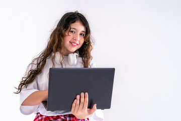 Naklejka premium Caucasian middle schoolgirl with laptop pc and headphones smiling in a studio on a white background. Distance education, free time, technology and internet concept.