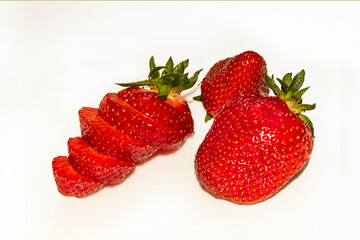 Two whole strawberries and one cut into circles, with sepals on a white background. Juicy bright tasty summer. red berries. Gifts of nature, food, healthy food, vitamins. background, postcard