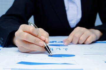 Businessman holding a profitability statistics analysis pen from a graph document in hand  to plan profit.