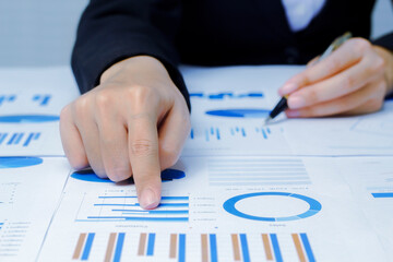 Businessman holding a profitability statistics analysis pen from a graph document in hand  to plan profit.