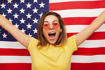 Excited young woman screaming and raising US flag