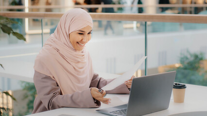 Young islamic woman sitting in cafe conducting online lesson talking on video conference using...