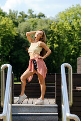 Young woman in yellow tank top and red shirt tied at the waist enjoys the sun