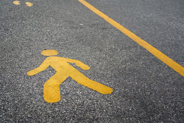 A pedestrain walking lane with human icon on asphalt road surface. Transportation symbol for safety background concept.