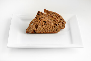Sliced rye bread on square plate on white background