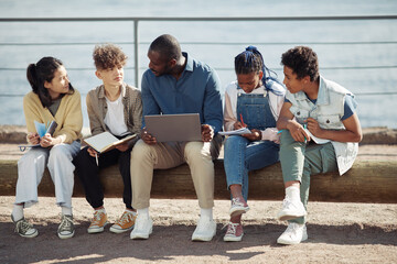 Full length shot of diverse group of kids with male teacher using laptop outdoors during Summer...