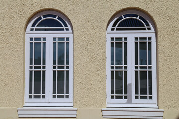 A closeup view of a pair of painted arched multipaned art deco windows. 