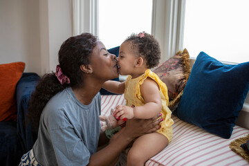 Mother kissing baby daughter (12-17 months) at home