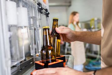 Close up of male brewer hands in a brewery filling bottles with beer.