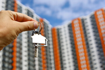 Real estate agent, keychain in shape of a house and key in male hand on background of new...