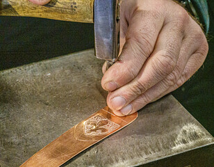 Sarajevo, Bosnia - May 2, 2022 - Metalsmith adds ornamentatiion to new bookmark.