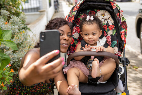 Mother taking selfie with baby daughter (12-17 months) in stroller