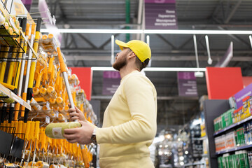 a man chooses a roller with brushes in a construction hypermarket
