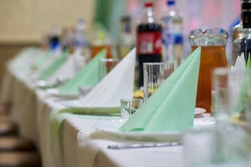 Festive table decorated in green tones with food and drinks in the background in defocus