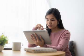 Young asian woman using digital tablet at home. Online learning, home school concept.