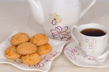 There is a pot of tea and homemade sweet cookies on the dining table.