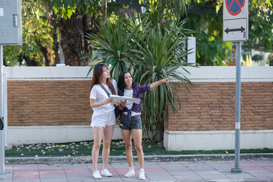 Woman tourist using navigation map to explore the city. two women friends moving around the city. Asian woman vivacious in thailand city with a beautiful beaming smile.