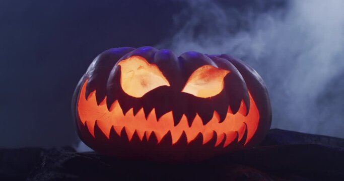 Video of halloween carved pumpkin with smoke on black background