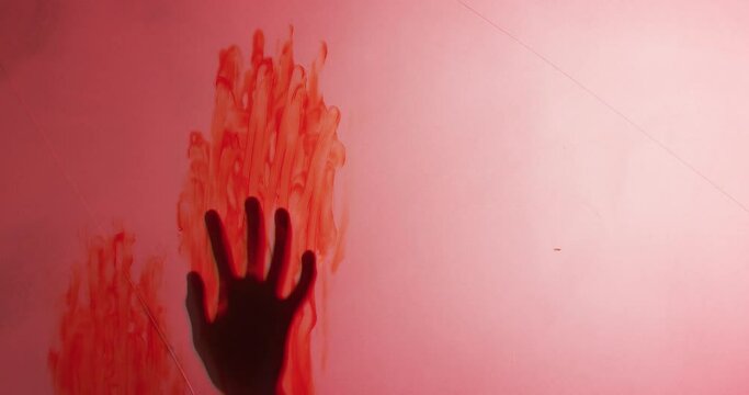 Video of silhouette of hand with blood stains moving on red background