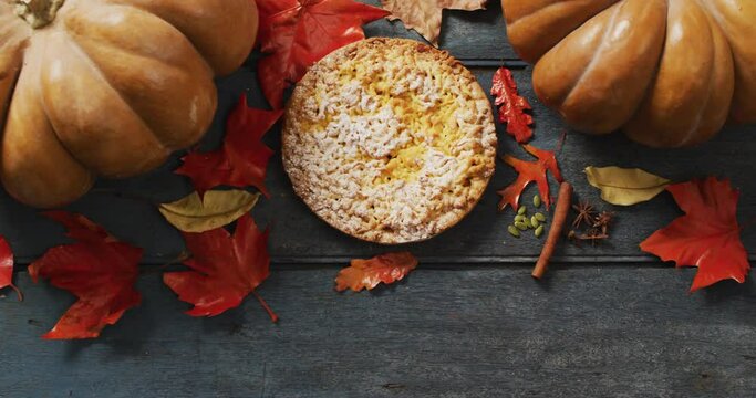 Video of autumn leaves, pumpkin, spices and pie on wooden background