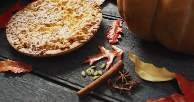 Video of autumn leaves, pumpkin, spices and pie on wooden background