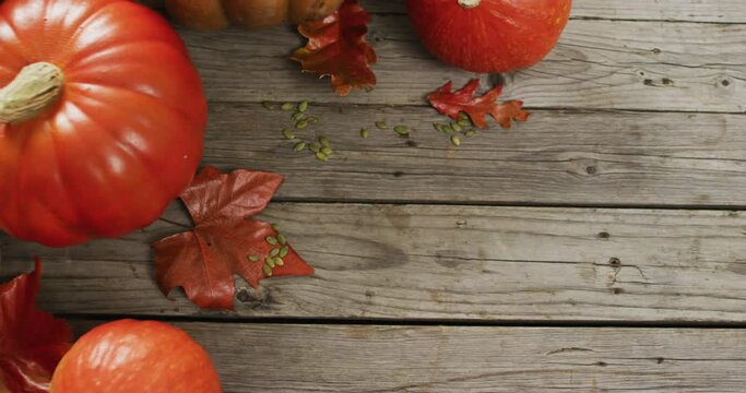 Video of pumpkins and autumn leaves on wooden background