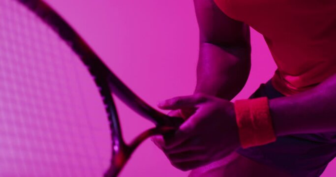 Video of midsection of african american female tennis player on neon pink lightning