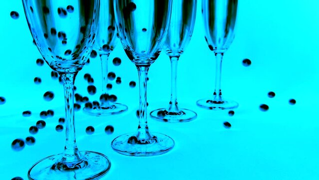 Falling white pearls next to wine glasses on a blue