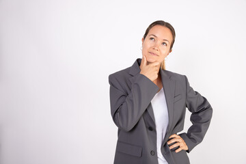 Portrait of young businesswoman standing with pensive expression. Caucasian woman wearing gray suit coat and white shirt thinking about something. Doubt and uncertainty concept
