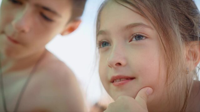 Portrait little cute girl playfully looks in different directions with her brother chewing something on background. Freedom lifestyle and traveling in holiday concept