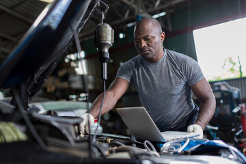 Mechanic using compute for Diagnostic  machine tools ready to be used with car. Car mechanic using a computer laptop to diagnosing and check up on car engines parts for fixing and repair