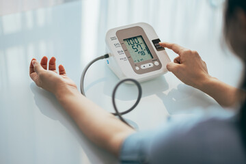 Adult woman measuring blood pressure at home