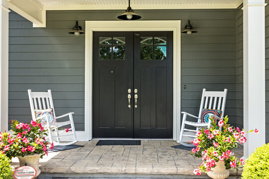 A front porch with two rocking chairs, stamped concrete floors, and double glass doors © Ursula Page
