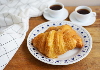 Breakfast in bed, fresh croissants and a cup of coffee on a wooden tray. Fine morning.