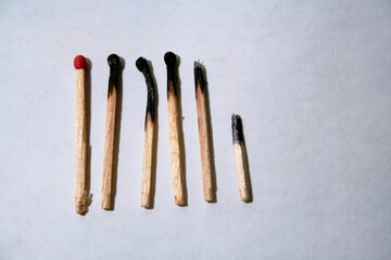 Fòsforos de madera apagados en lìnea con un cerillo sin prender de cabeza roja de potasio, forman un original diseño abstracto en contraste con fondo gris