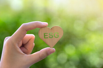 ESG concept of environmental, social and governance.hand holding wooden heart shape with esg word....