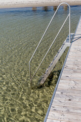 steel ladder at wooden pier on clear shallow waters at shore of Koge bay, Olsemagle Strand, Denmark