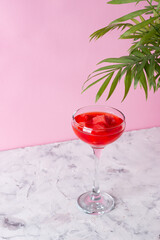 Watermelon juice in cocktail glasses and watermelon slices on a pastel pink background. Refreshing summer drink.