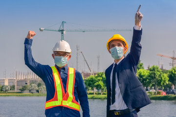 Asian engineer and foreman worker with touch pad discuss, plan working for the outdoors building construction site.