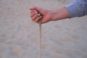 Sand rinnt durch die Hand einer Frau