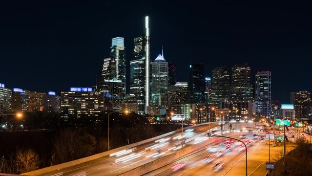 Time-lapse of car traffic transport on multiple lanes highway road, financial district buildings at night in Philadelphia, USA. America transportation, commuter lifestyle, American city life concept