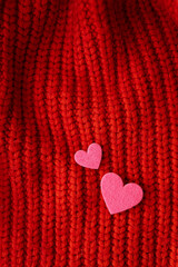 Decorative pink heart on a red knitted background, top view. Place for an inscription, vertical photo.